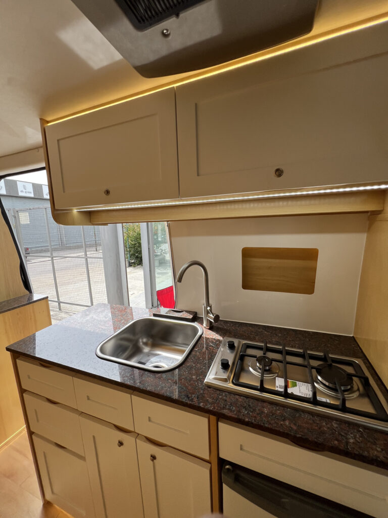 Vista lateral de cocina en motorhome Sprinter 515 con anafe y guardado
