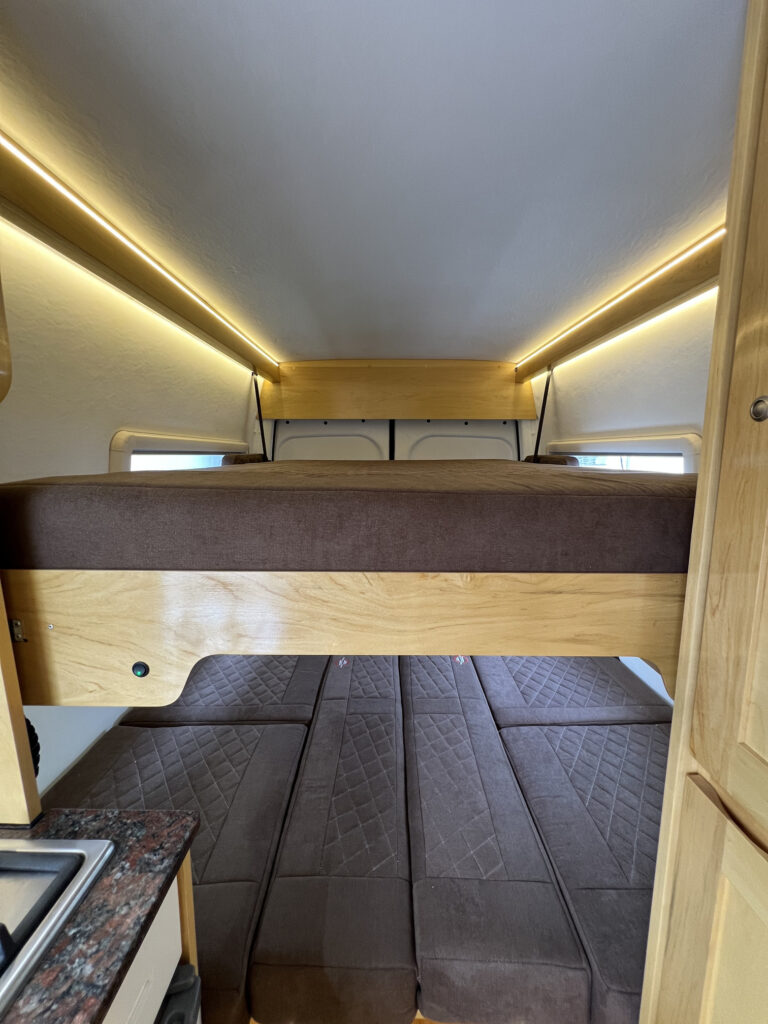 Cama levadiza elevada en motorhome Sprinter 515 mostrando espacio inferior