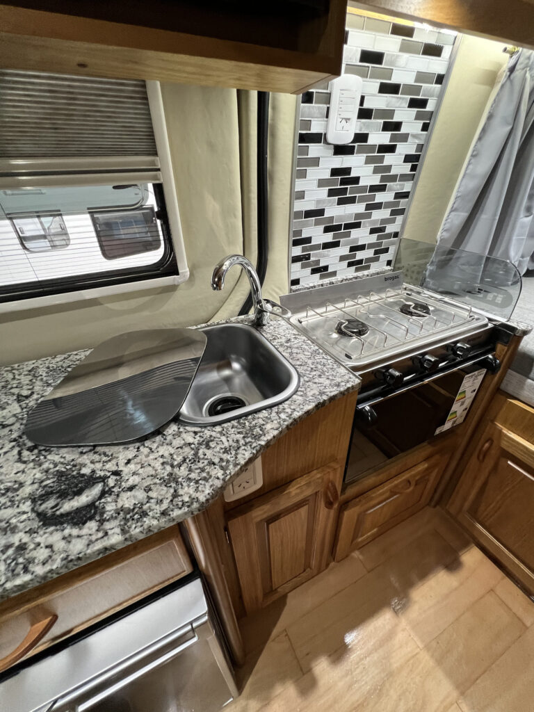 Vista lateral de cocina en motorhome Sprinter 316 con muebles y anafe